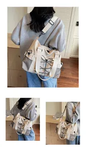 Detail of cream nylon travel bag featuring adjustable wide strap and elastic drawstrings