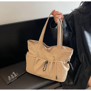 Detail of cargo-style tote bag featuring multiple drawstring pockets and nylon texture