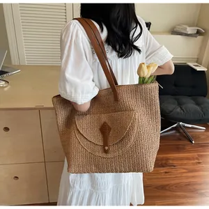 Detail of hand-woven straw tote bag showing brown leather buckle and fine textured weave