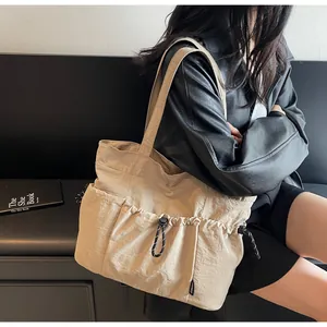 Detail of beige nylon tote bag featuring front drawstring pocket and side compartment
