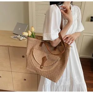 Detail of hand-woven straw tote bag with brown leather straps and front flap pocket