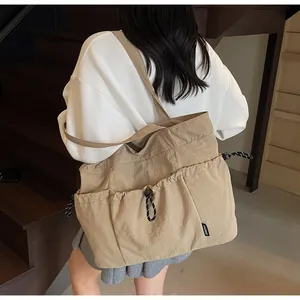 Detail of khaki shoulder tote bag with adjustable drawstring pockets and SHUNUO label