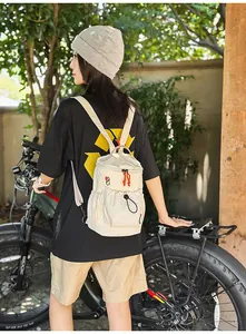 Detail eines cremefarbenen Nylonrucksacks mit orangefarbenem Reißverschluss und Kordelzug