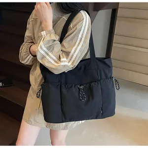 Detailed macro view of large black tote bag with functional drawstring side pocket details