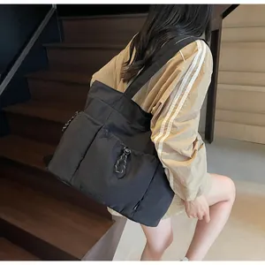 Detail view of large black nylon tote bag with front pocket and decorative drawstring