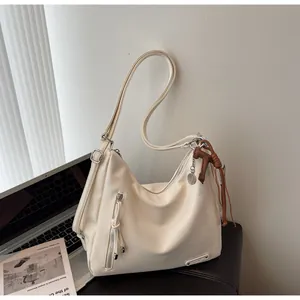 Détail du sac hobo en cuir PU crème avec ferrures argentées et pendentif tressé
