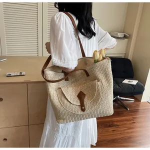 Detail of hand-woven straw tote with brown leather straps and front pocket detail