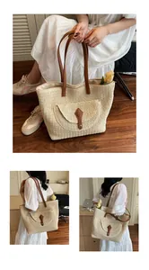 Close-up of woven paper rope tote bag with brown faux leather handles and front pocket detail