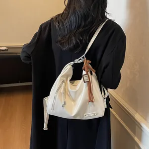 Grand sac cabas blanc en similicuir avec fermetures éclair et pompon porté par un mannequin