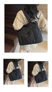 Close-up of black drawstring tote bag with woven cords and spacious pockets on wooden stairs