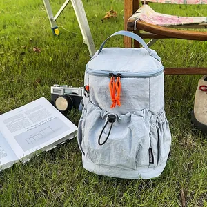 Minimalistischer hellblauer Nylon Rucksack mit orangefarbenen Kordeln im Grünen