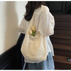 Detail of cream crochet tote bag with openwork knit pattern and wide shoulder strap
