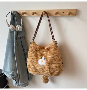Détail d'un sac à bandoulière en peluche chat roux accroché à un crochet en bois