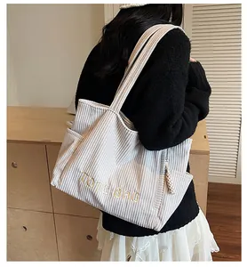 Detailed side view of corduroy tote bag showing large capacity and embroidered text