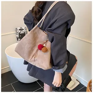 Detail of light brown suede tote bag with plush charms and tassels for autumn fashion