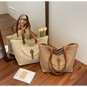 Detail of hand-woven straw tote bags in beige and brown with leather flap and metal clasp