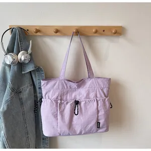 Detailed view of purple nylon tote bag with functional exterior pockets and drawstring detail