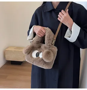 Dettaglio borsa tote in peluche marrone con ricamo occhi e tracolla in pelle