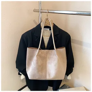 Detail of a large beige suede tote bag showing stitching and slim shoulder straps