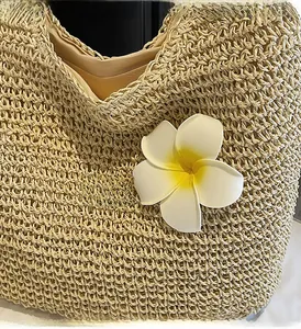 Détail d'un sac en paille tissé main avec fleur de frangipanier et doublure brune