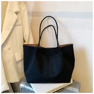 Close-up of black suede tote bag with brown lining and minimalist vertical stitching detail