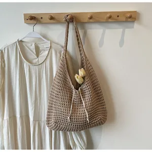 Detail of a brown crochet knit tote bag featuring hollow mesh structure and drawstring tassels