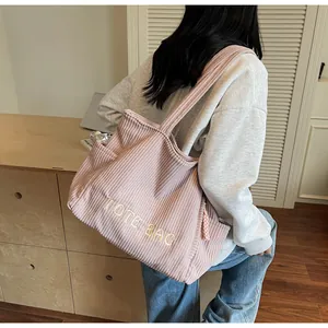 Detailed view of pink corduroy tote bag showing embroidered text and shoulder strap