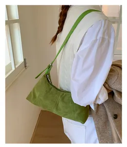 Detail of sage green suede baguette bag featuring smooth zipper and slim shoulder strap