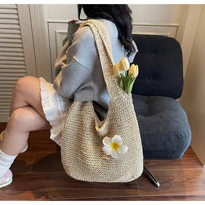 Détail du sac cabas beige tressé avec breloque fleur blanche dans un intérieur douillet