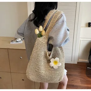 Détail du sac cabas en paille tissée avec fleur de frangipanier et longue bandoulière