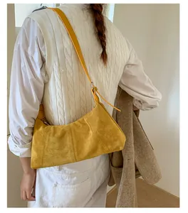 Detail view of yellow matte suede hobo bag showing texture and stitching on a female model