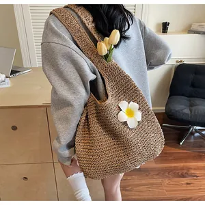 Détail d'un grand sac fourre-tout en paille avec fleur de frangipanier pour la plage