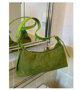 Detail of green suede baguette bag with decorative stitching and silver metal zipper