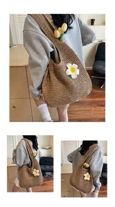 Détail du grand sac cabas en paille tressée orné d'une fleur blanche en trois dimensions