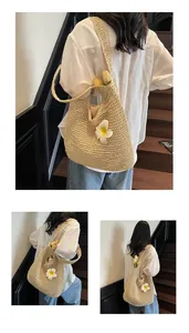 Détail d'un sac bandoulière en paille tissée avec fleur blanche pour vacances à la mer