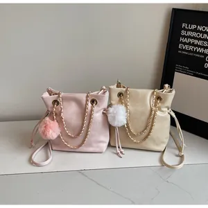 Détails des sacs seaux rose et beige avec bandoulières en chaîne et pompons en peluche
