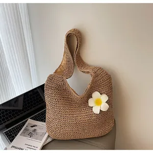 Détail du sac à bandoulière en paille tressée avec fleur de frangipanier blanche pour plage
