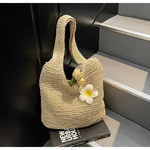 Gros plan sur un sac cabas en paille tressée beige avec frangipanier pour la plage