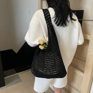 Black hollow woven knit tote bag with large capacity and floral accent shown on model