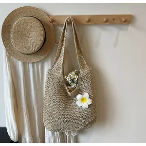 Détail d'un sac cabas en paille tissé à la main avec fleurs blanches sur crochet