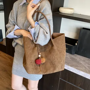 Large brown suede tote bag with fringe pompom detail shown on model for daily use