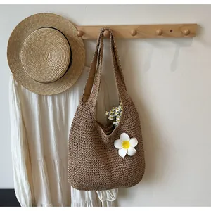 Détail d'un sac à bandoulière en paille tissé main avec fleur blanche pour plage estivale