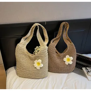 Détail de sacs cabas en paille tressée avec de grandes fleurs 3D en crème et kaki