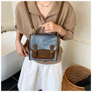 Close-up of vintage blue washed fabric handbag with brown leather and gold buckles