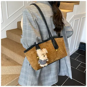 Détail du sac cabas en daim marron avec bordure en cuir et pendentif chiot peluche
