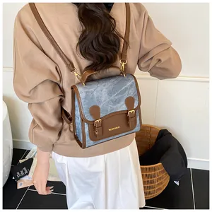 Detailed back view of vintage blue denim and brown leather mini backpack on model