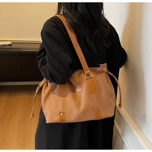 Brown faux suede tote bag with drawstring detail and leather strap on shoulder