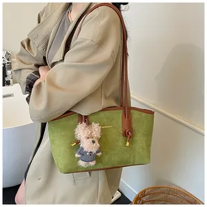 Gros plan du sac fourre-tout en daim vert avec lanières brunes et breloque chien en peluche
