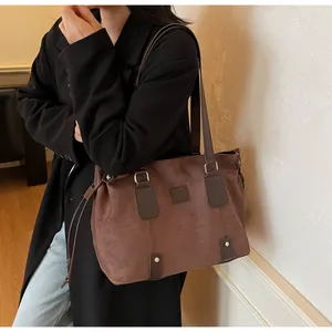 Detail of dark brown suede tote bag with drawstring accents and silver metal hardware