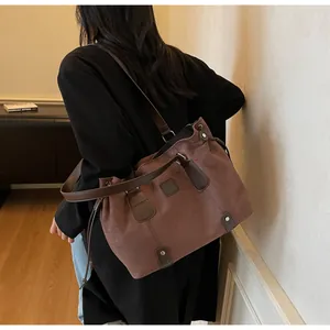 Detail view of coffee-colored suede tote bag featuring a drawstring side and leather handle